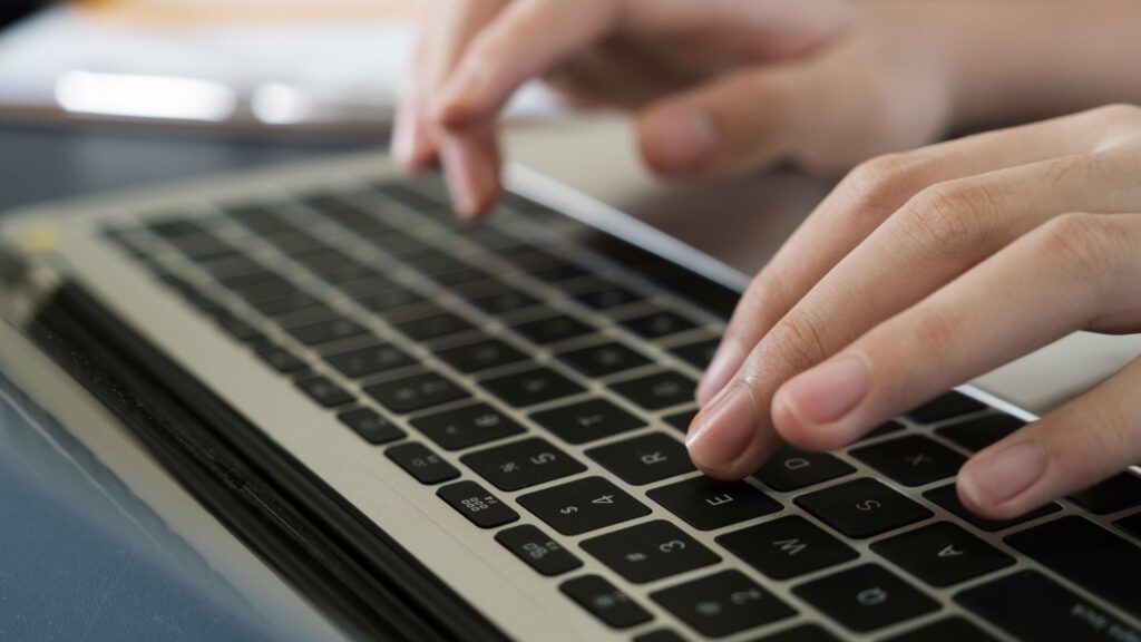 Two hands typing LSI keywords on laptop keyboard