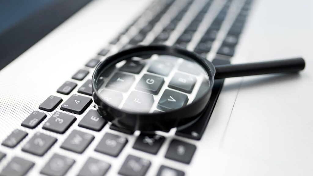 Magnifying glass on laptop keyboard searching for long tail keywords