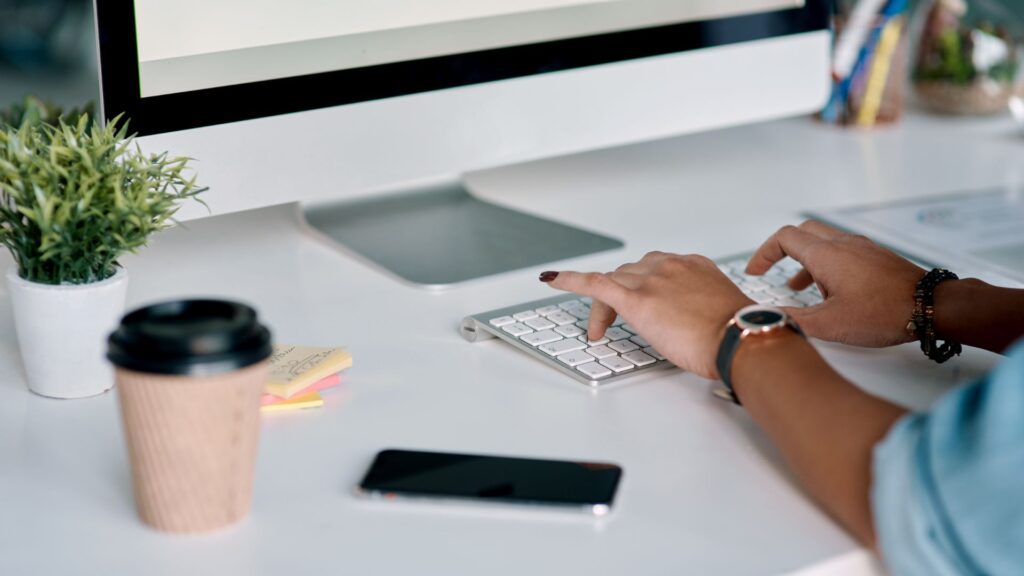 Hands on computer keyboard on desk practicing web copywriting