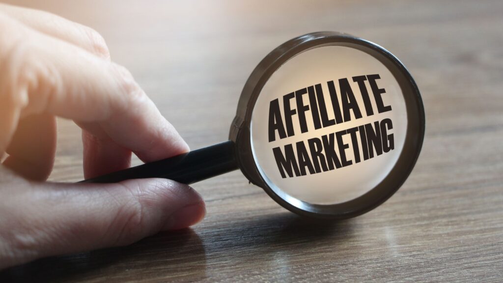 hand holding magnifying glass with the words "affiliate marketing" in it.