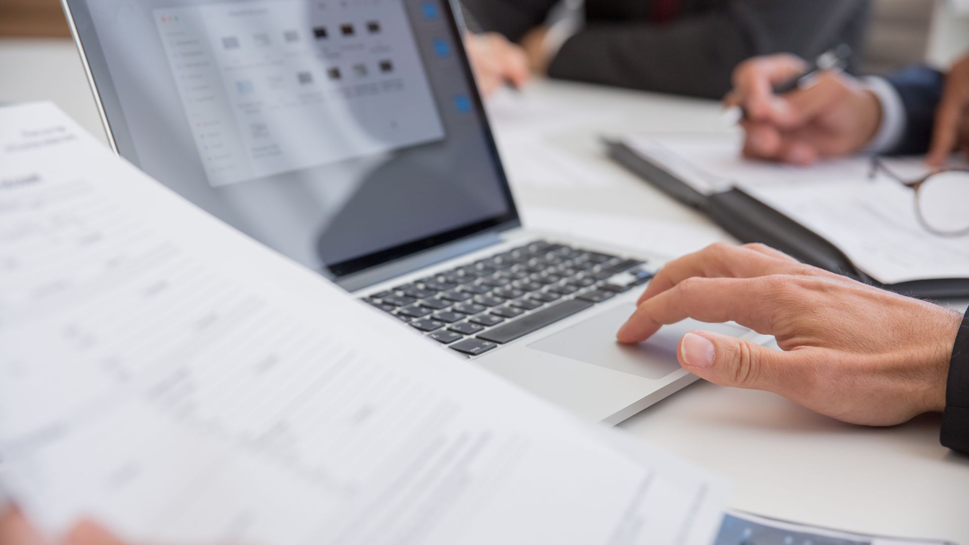 Person sitting by laptop holding a piece of paper practicing content curation