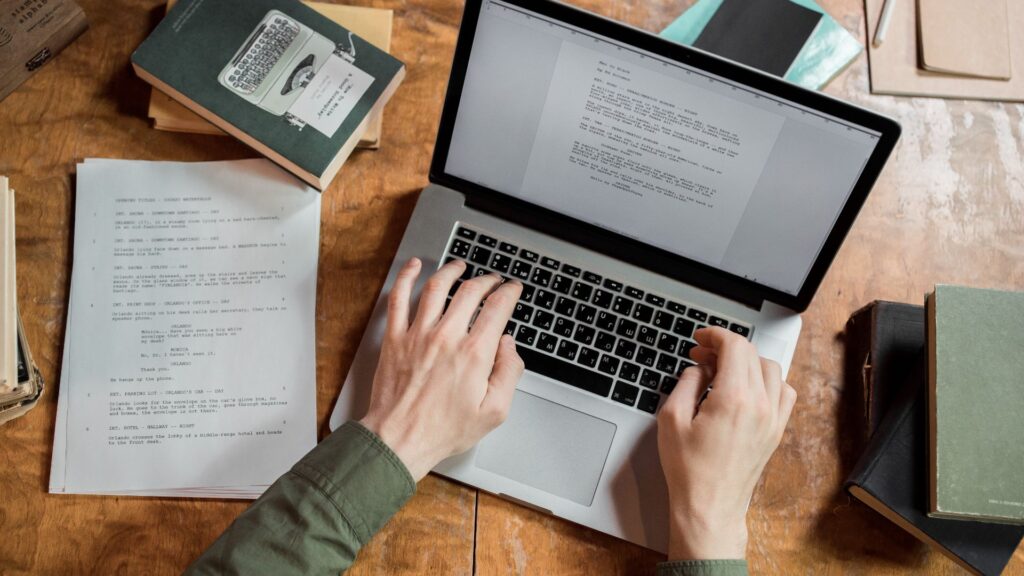 Laptop, papers, and a book on a desk.