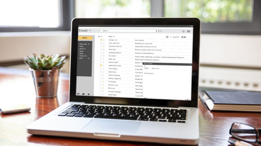 Laptop on desk with an email list on the screen.