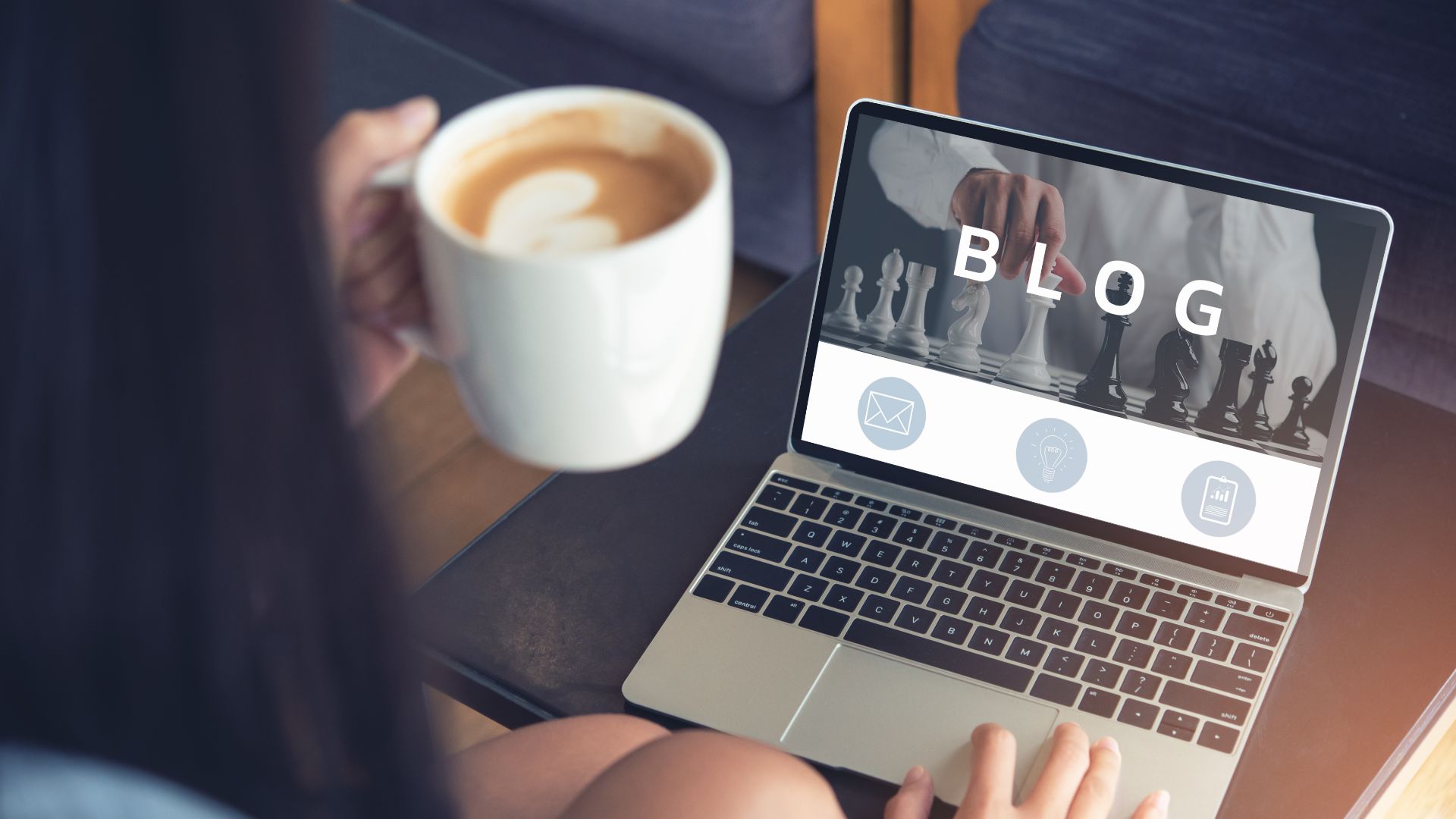 Woman holding cup of coffee in front of laptop with "blog" written on the screen.