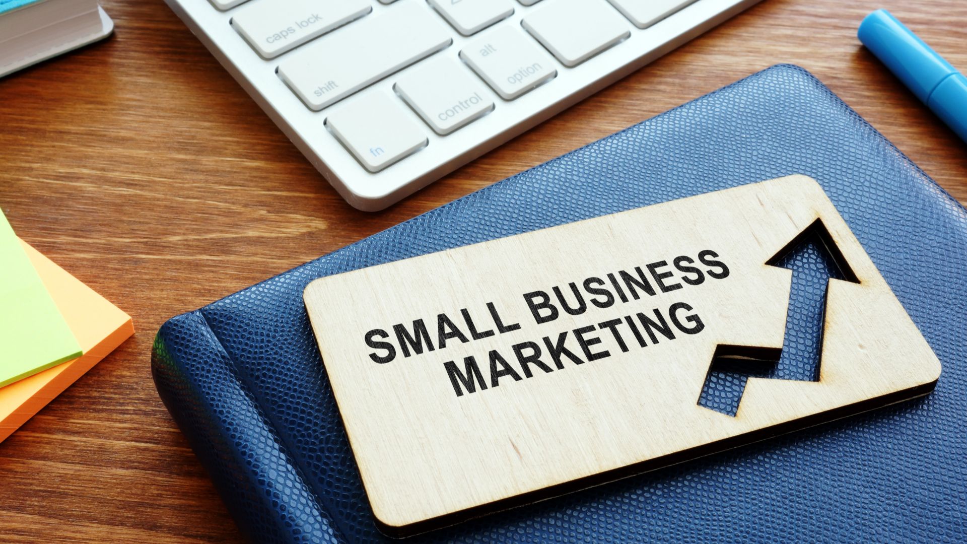 Sign on a desk saying "small business marketing" next to a laptop keyboard.