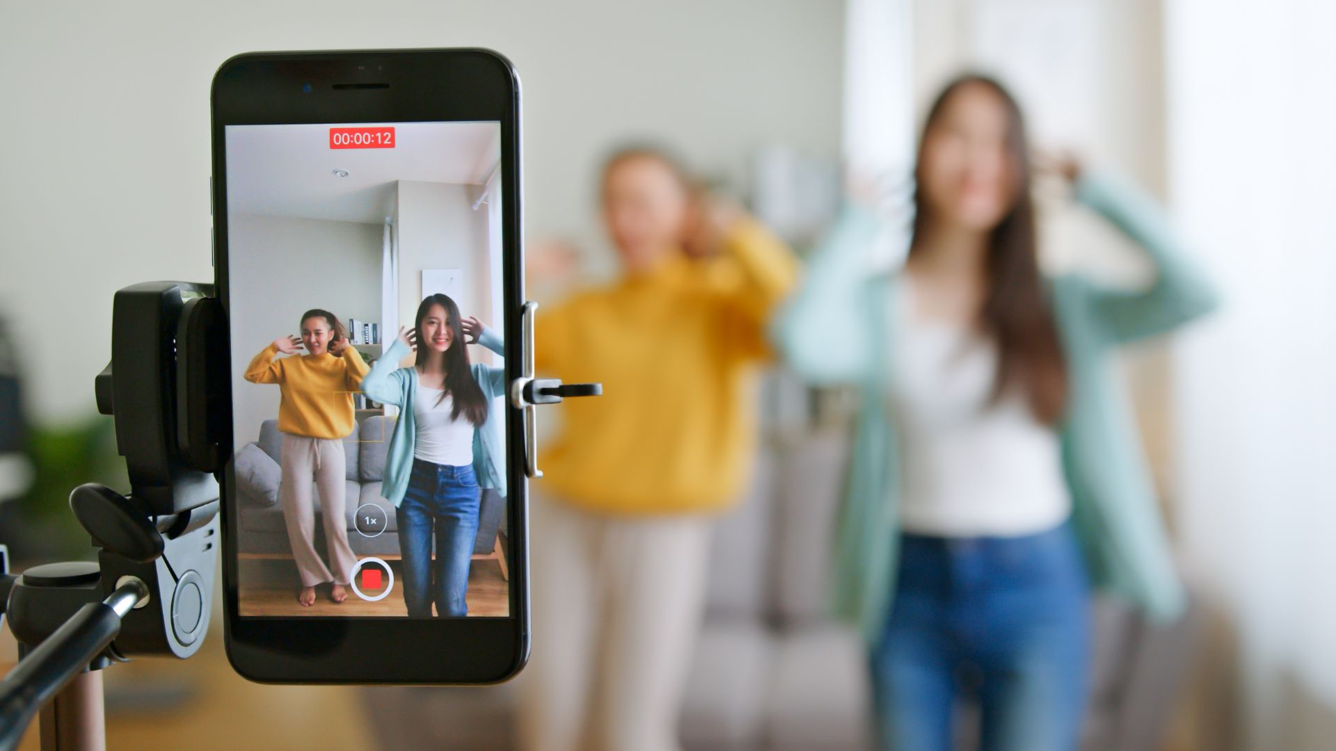 Two women dancing in front of smartphone camera recording a TikTok video