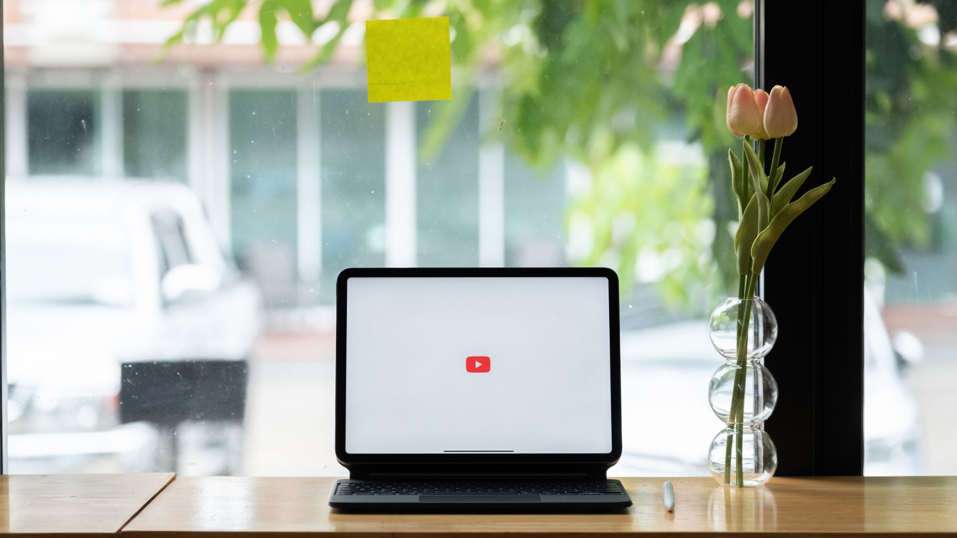 Laptop with a YouTube logo on the screen standing in a window.