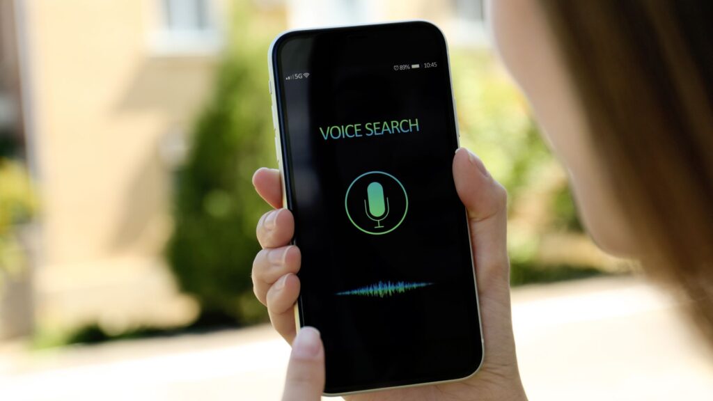 Woman holding a smartphone performing a voice search.